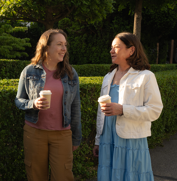 Woman standing in bright kitchen, holding a basket with vegetables and smiling